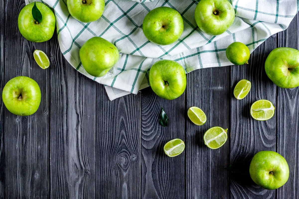 Fototapeta na stole leżą limonki i zielone jabłka